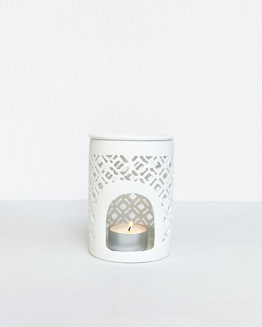 Matt white lattice cut wax burner with lit tea light inside.